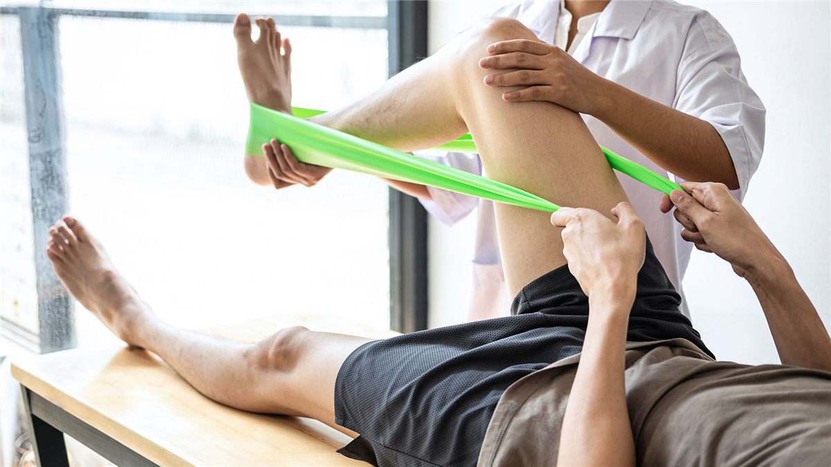 Fisioterapeuta auxiliando um paciente em exercício com faixa elástica