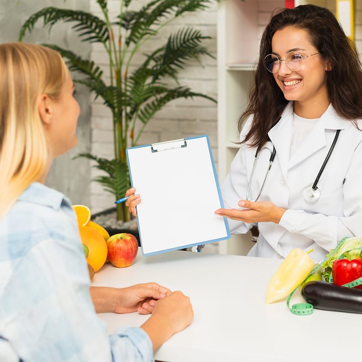 Nutricionista sorrindo enquanto apresenta um plano alimentar a uma paciente